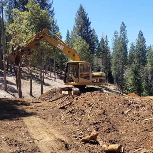 Caterpillar 312 excavator working on clearing for a building site